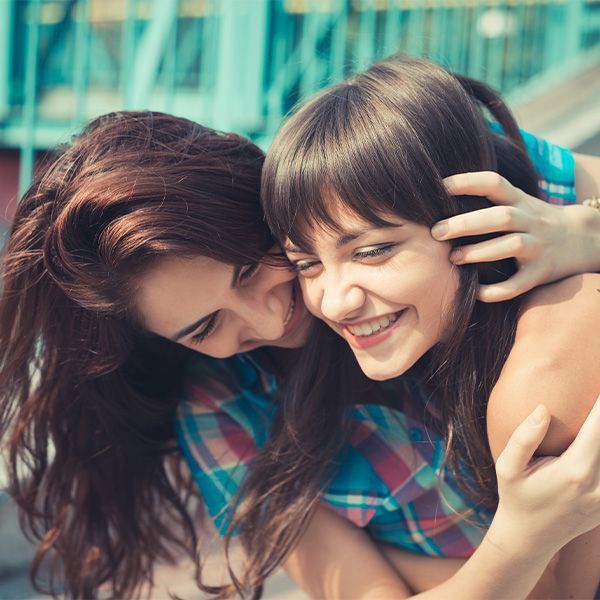 Two young women hugging each other and smiling. 