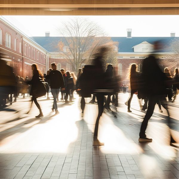 A blurry picture of a crowd of people walking in front of a building.