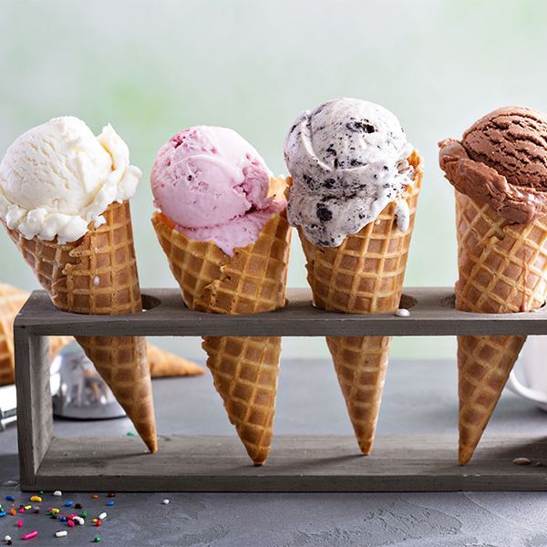 Four ice cream cones in a holder: vanilla, strawberry, cookies and cream, and chocolate.