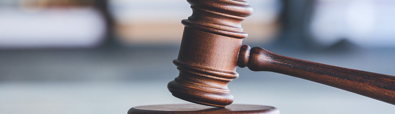 Wooden gavel resting on a surface, in a blurry setting.