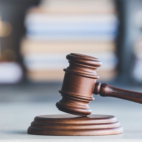 Wooden gavel on a round block; blurry background of books.