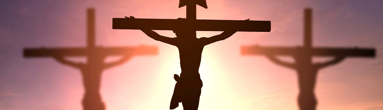 Silhouetted crucifixions against a sunset, representing the crucifixion of Jesus Christ.