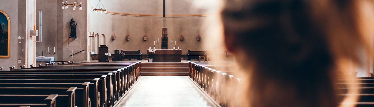 View of a church interior with pews and altar, seen from behind a blurry figure.