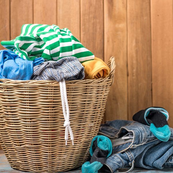 A wicker laundry basket filled with clothes is sitting on a table.