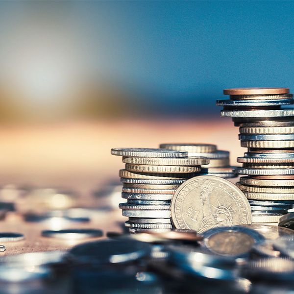Stacks of coins, some scattered, with a blurred blue and gold background.