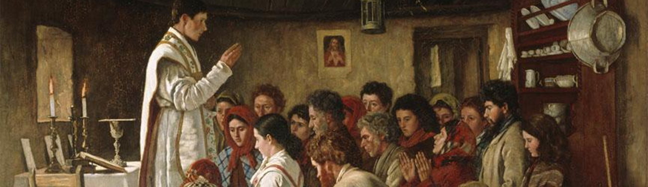 Priest in white robes addressing a seated group in a rustic thatched room.