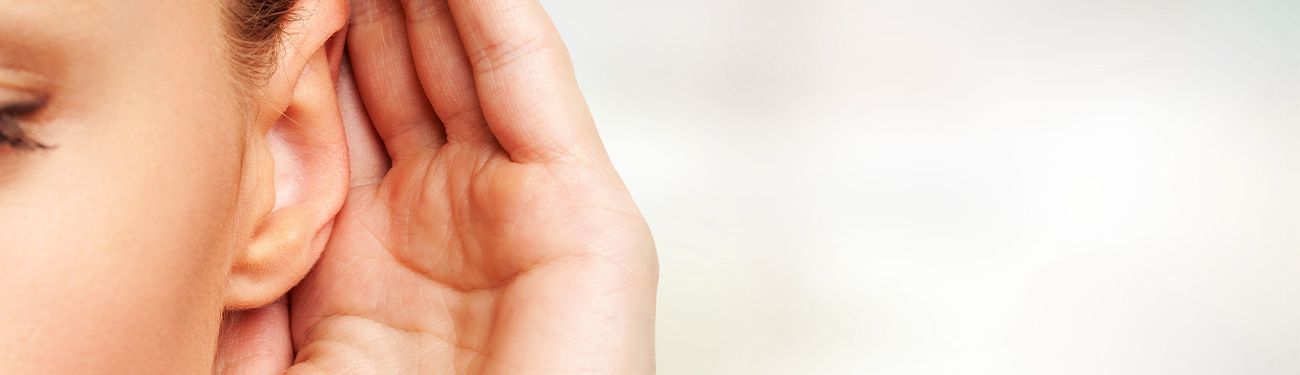 woman with a hand held to her ear to listen