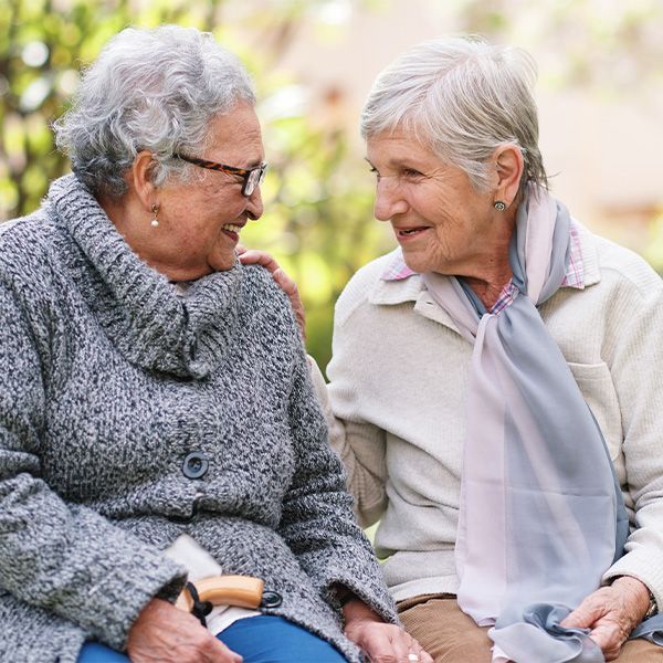 Two older women are sitting next to each other and talking.