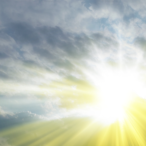 Bright sun breaking through cloudy sky with golden rays.