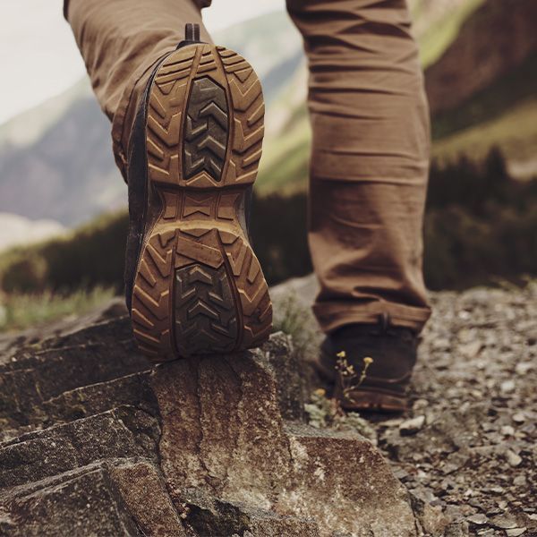A person wearing a pair of hiking boots is walking through a forest. 