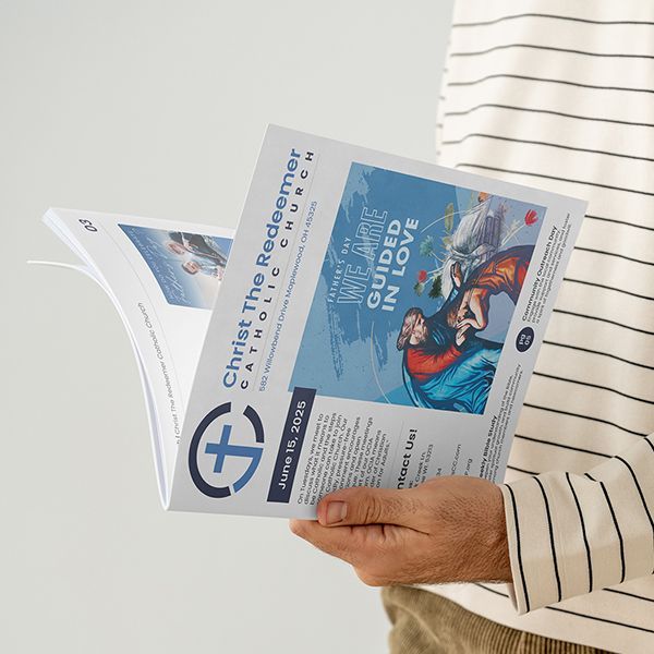 A person is holding a catholic church bulletin in their hands.