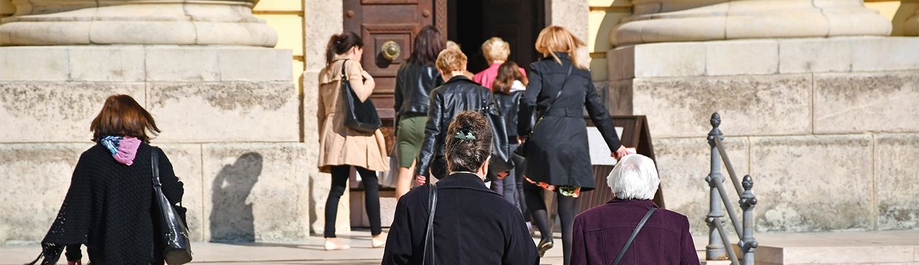 Parish priest typing on a laptop in an office.