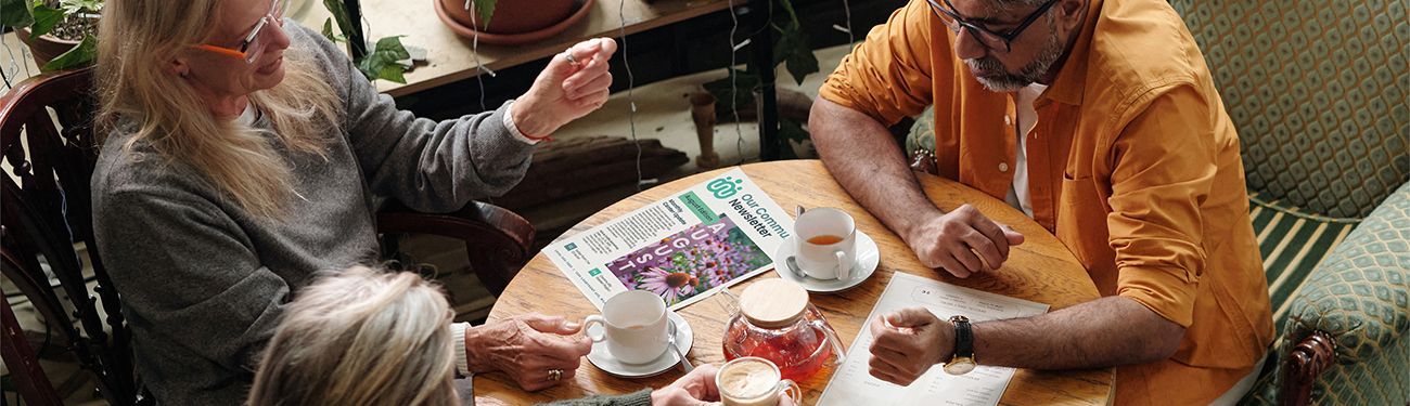 People sitting at a table with a newsletter drinking tea