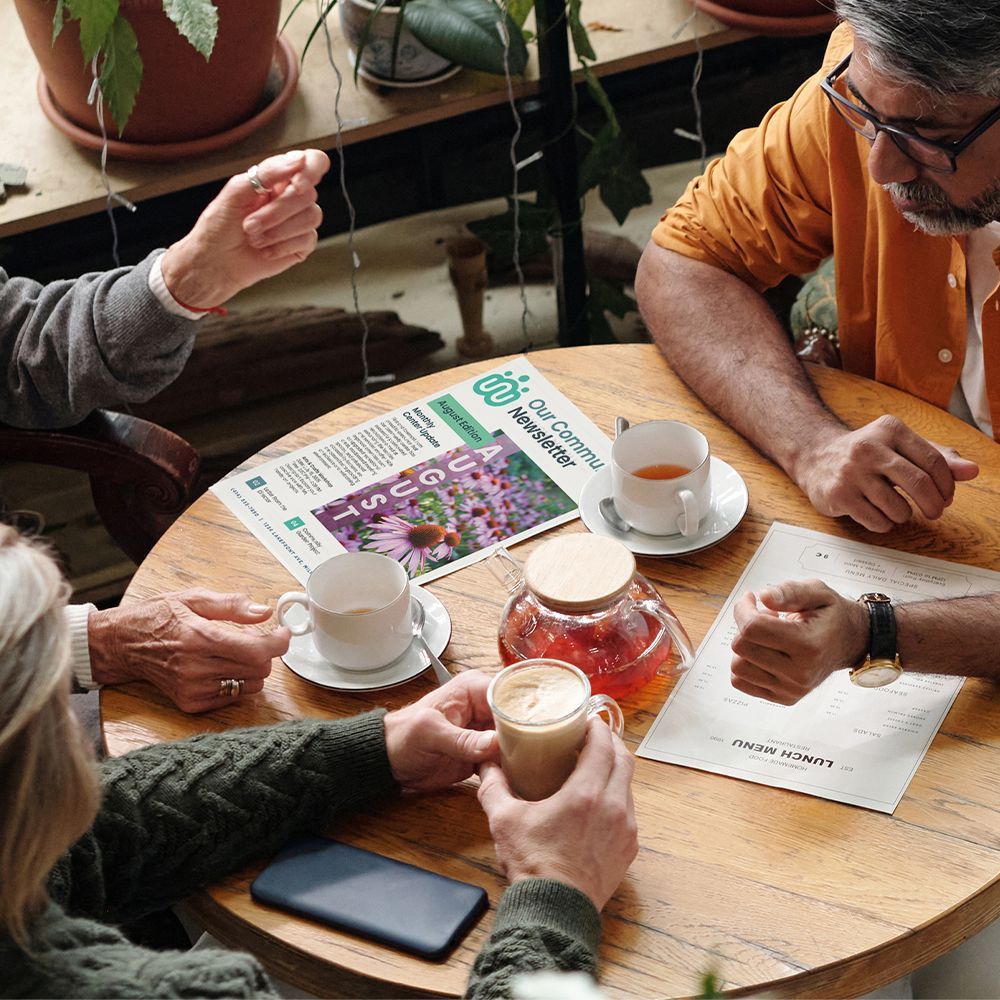 People sitting at a table with a newsletter drinking tea