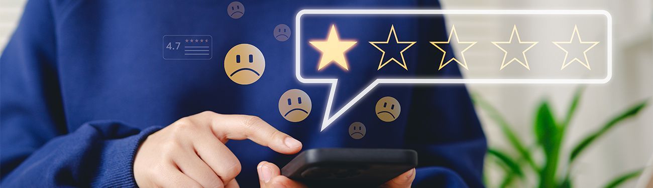 A person is holding a cell phone with a speech bubble showing a one star review.