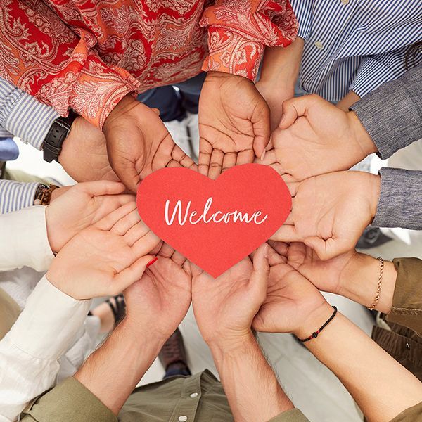 A group of people holding a red heart that says welcome.