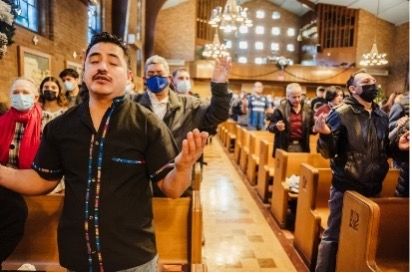 A man is standing in a church with his hands in the air.