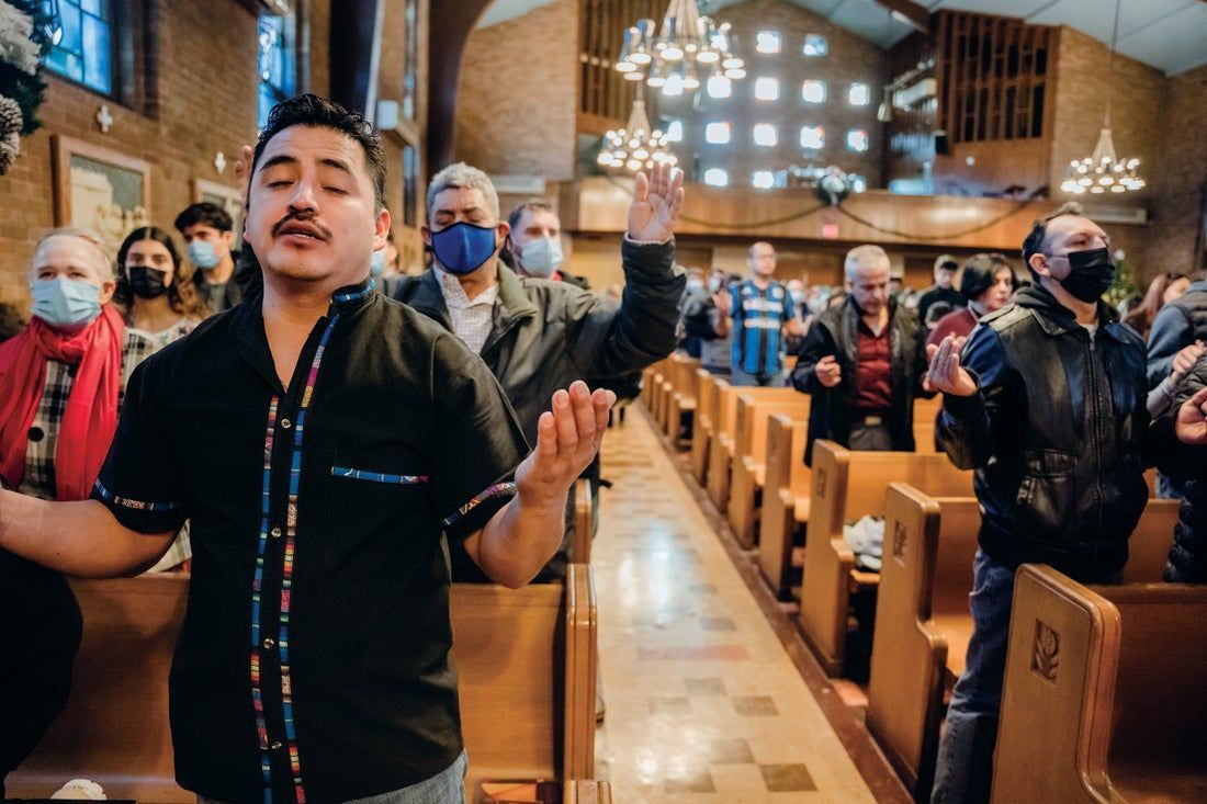 A man is standing in a church with his hands in the air.
