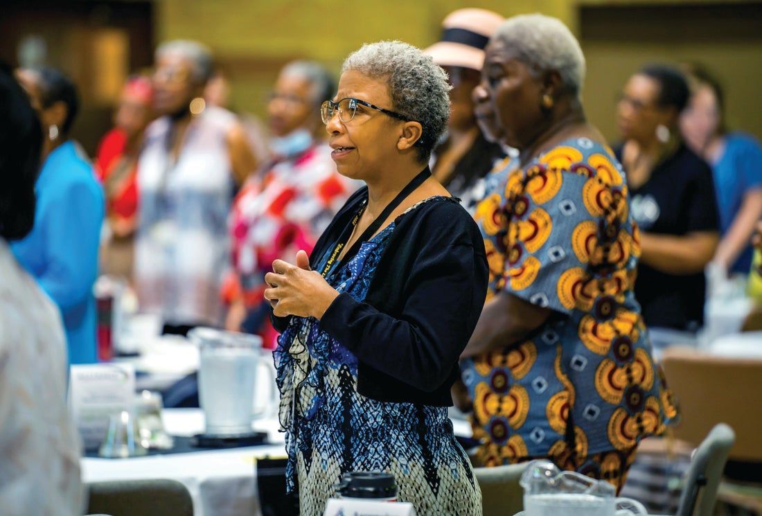 A woman is standing in a crowd of people at a table.