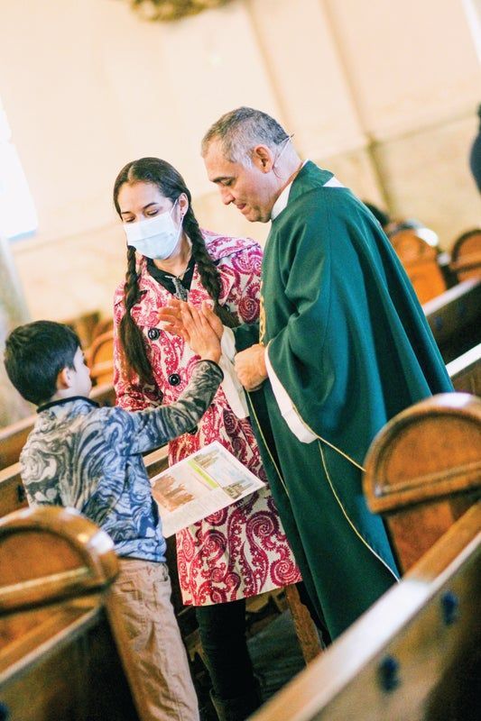 A child is high fiving a Priest in a church.