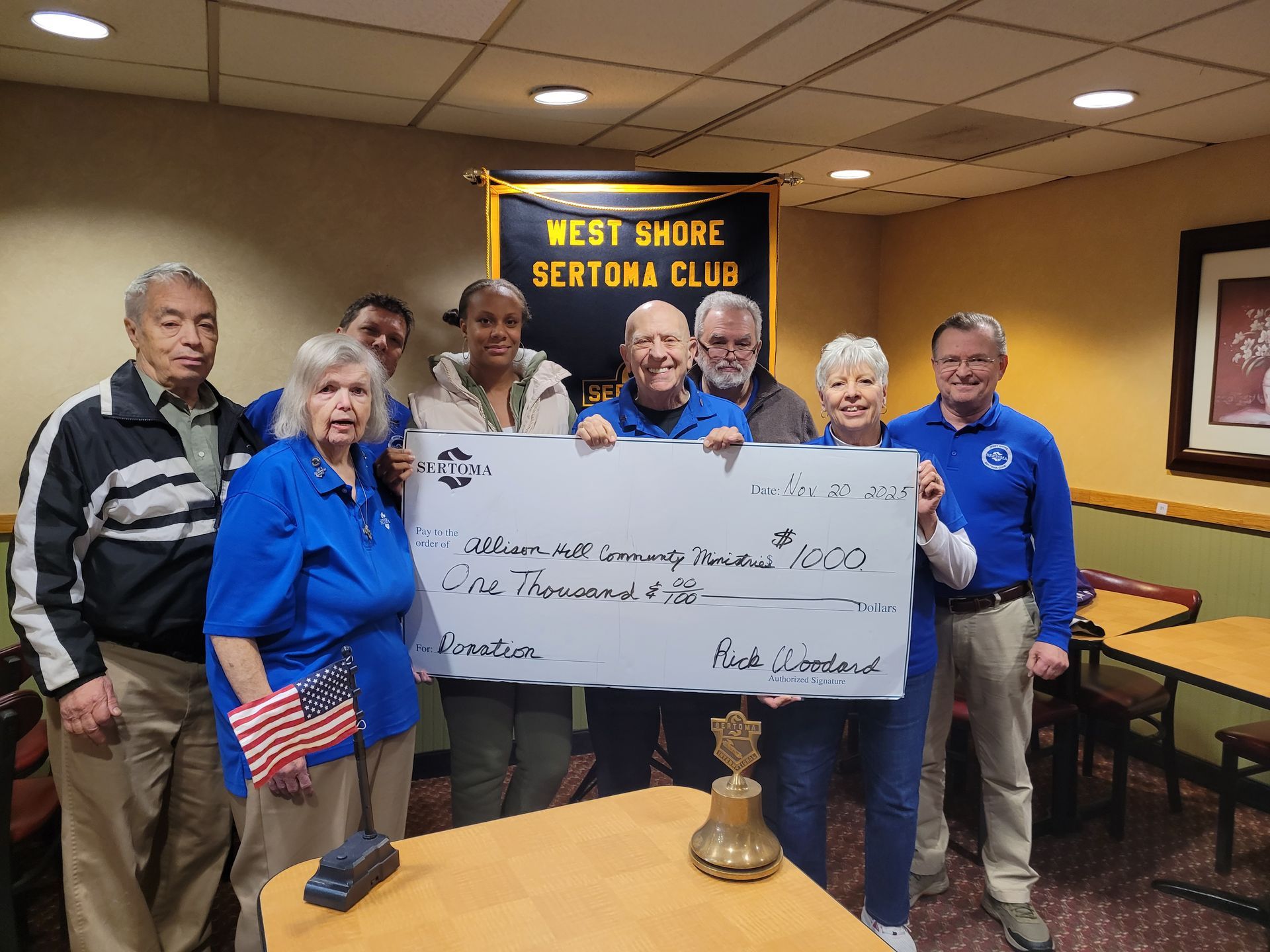 A group of people holding a large check in a room.