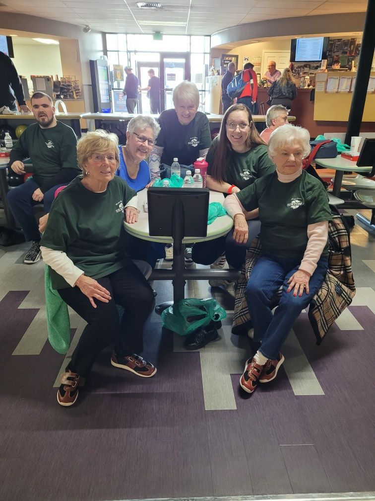A group of people are sitting around a table in a bowling alley.