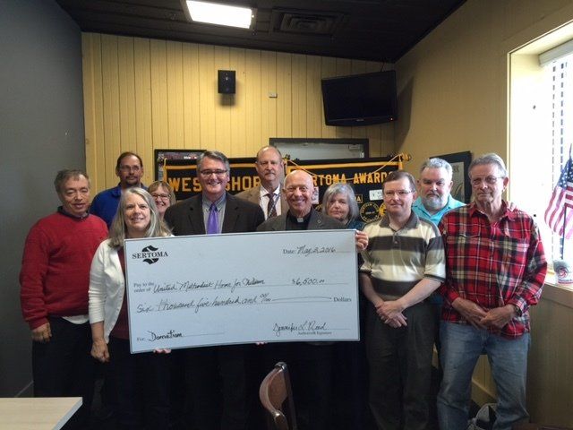 A group of people holding a large check in a room.