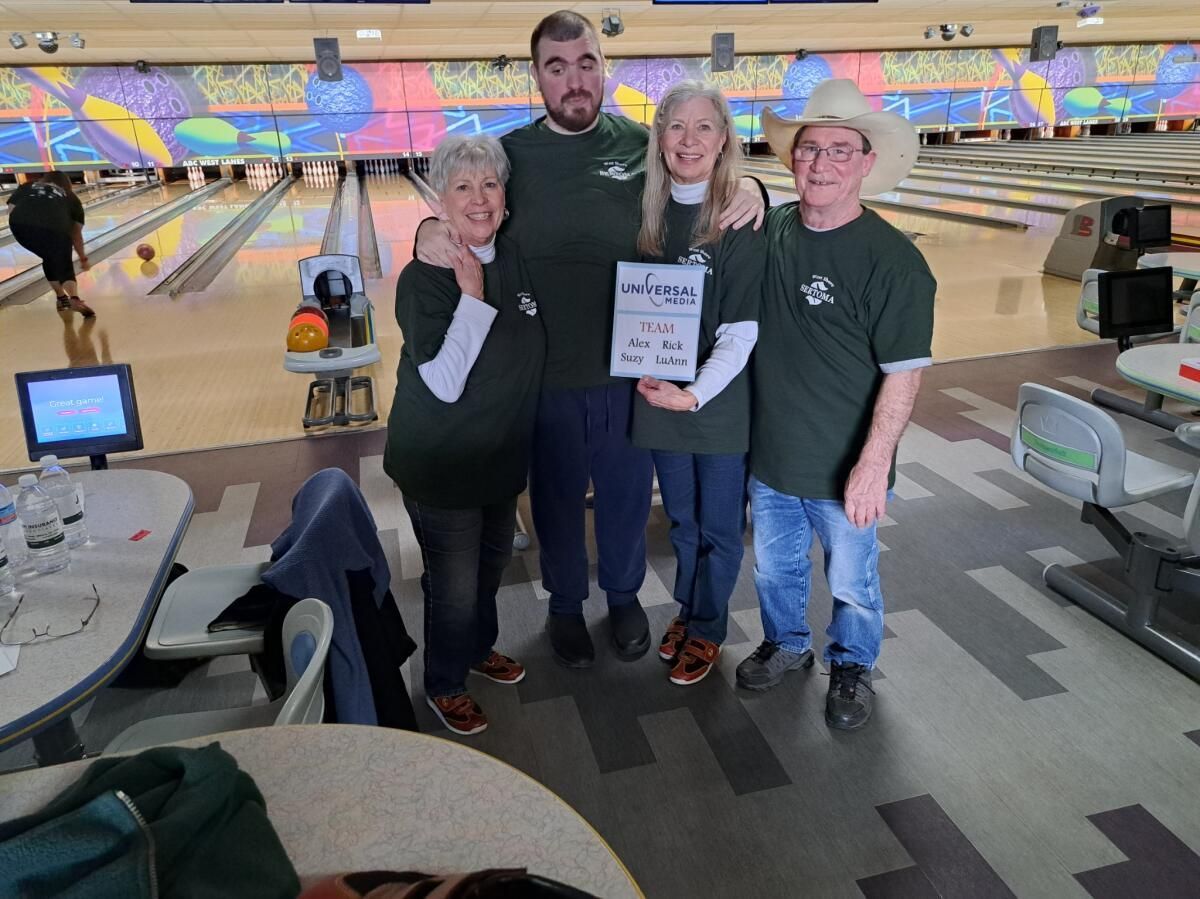 A group of people are posing for a picture in a bowling alley.