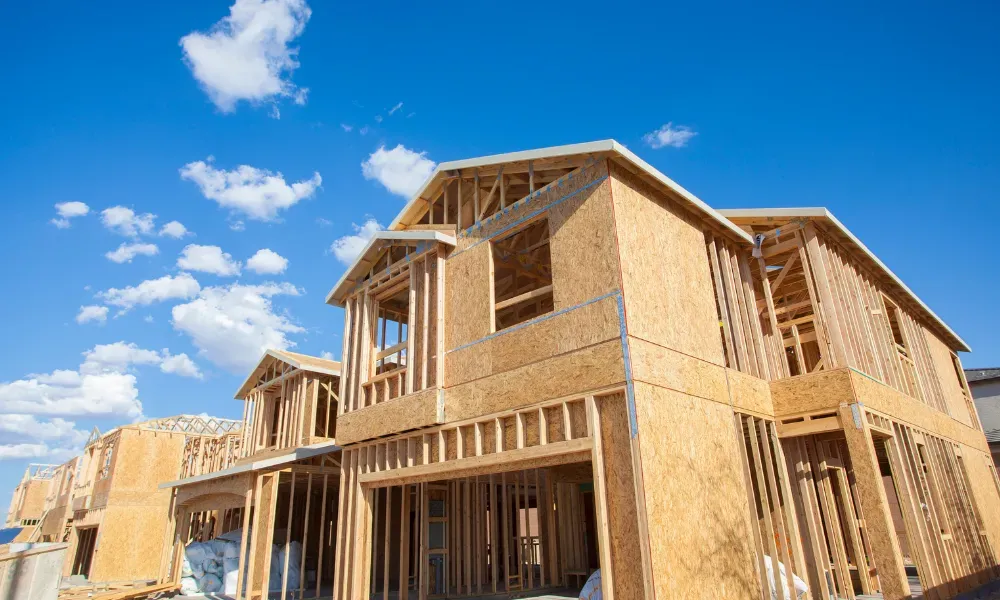 Wood frame house under construction against a blue sky with clouds.