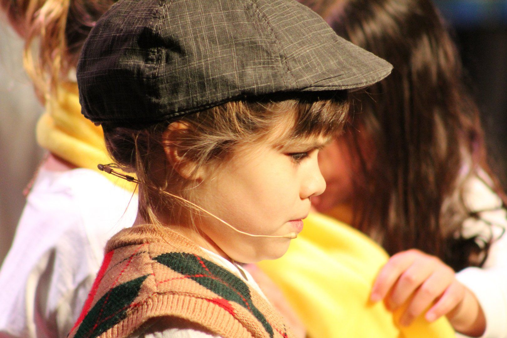 A little girl is wearing a hat and a microphone.
