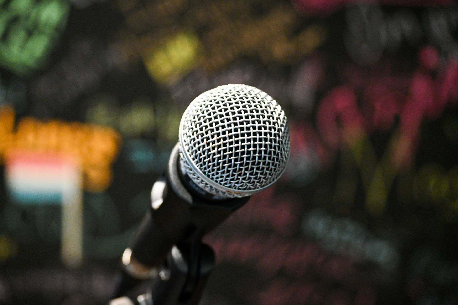 A close up of a microphone on a stand in front of a chalkboard.