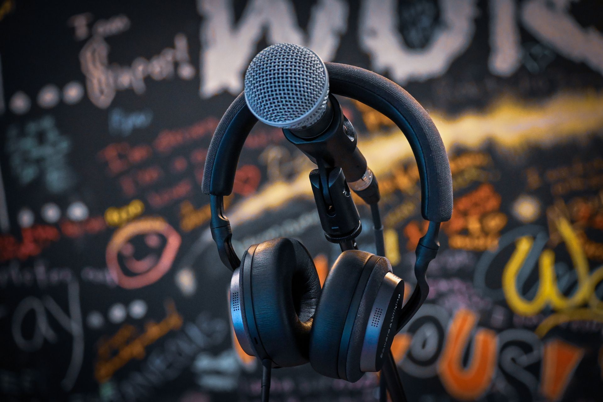 A pair of headphones and a microphone are sitting in front of a chalkboard.