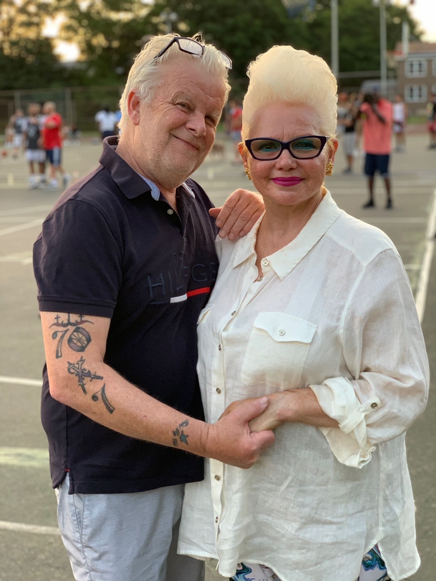 A man and a woman are standing next to each other on a tennis court.