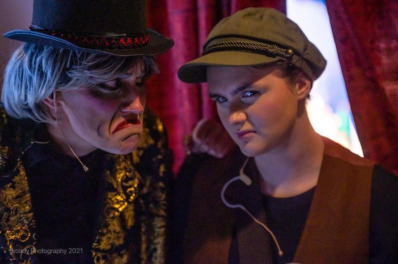 A man and a woman are standing next to each other in front of a red curtain.