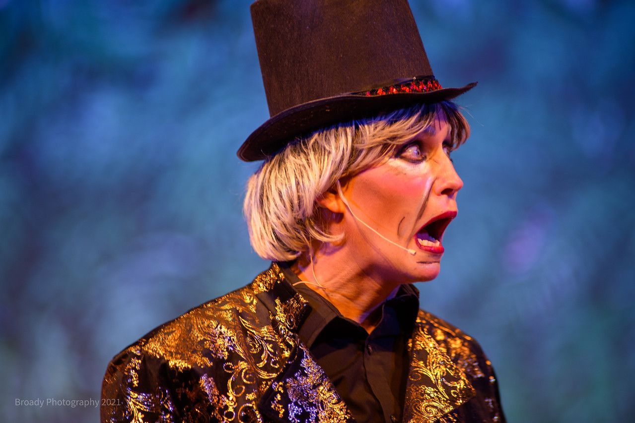 A woman is wearing a top hat and a gold jacket.