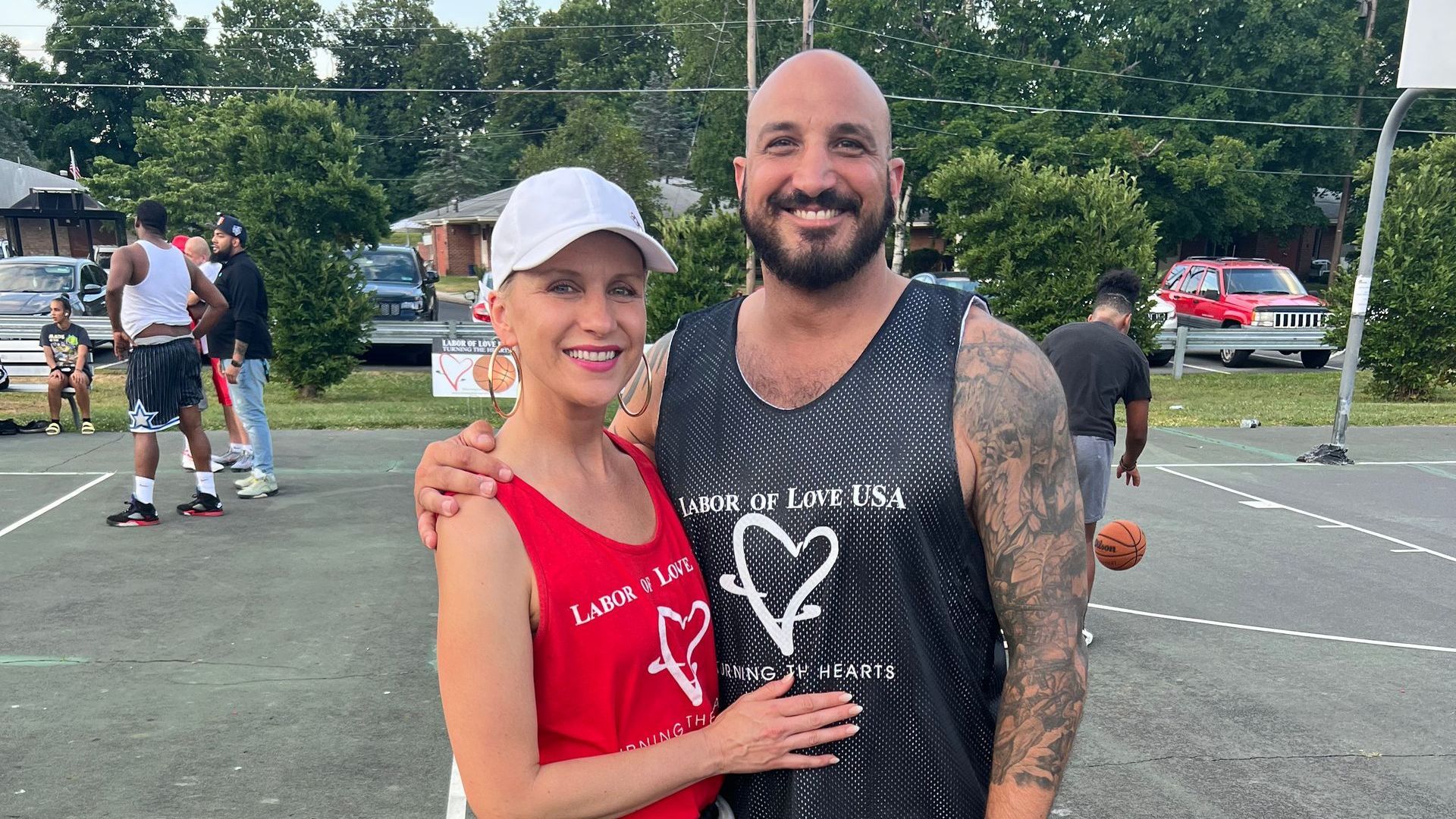 A man and a woman are posing for a picture on a basketball court.