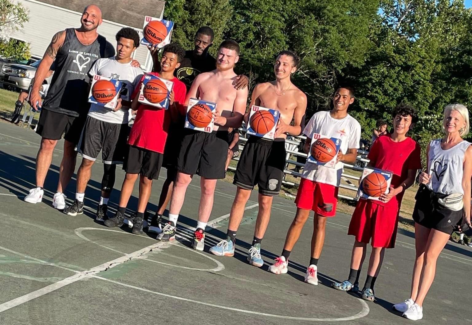 A group of people are standing on a basketball court holding basketballs.