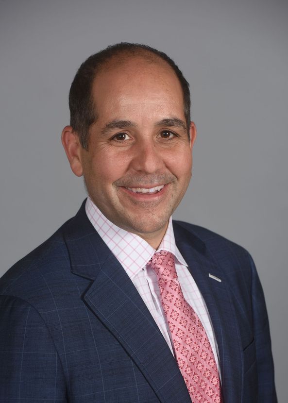 A man is holding a dog in his arms and the dog is wearing a sweater.