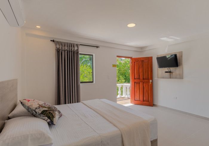 Un dormitorio con una cama y un televisor en la pared.