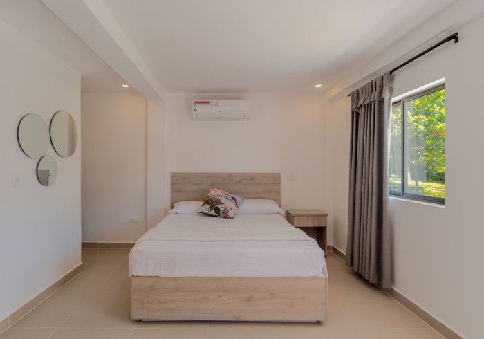 Un dormitorio con una cama, mesita de noche, espejos y una ventana.