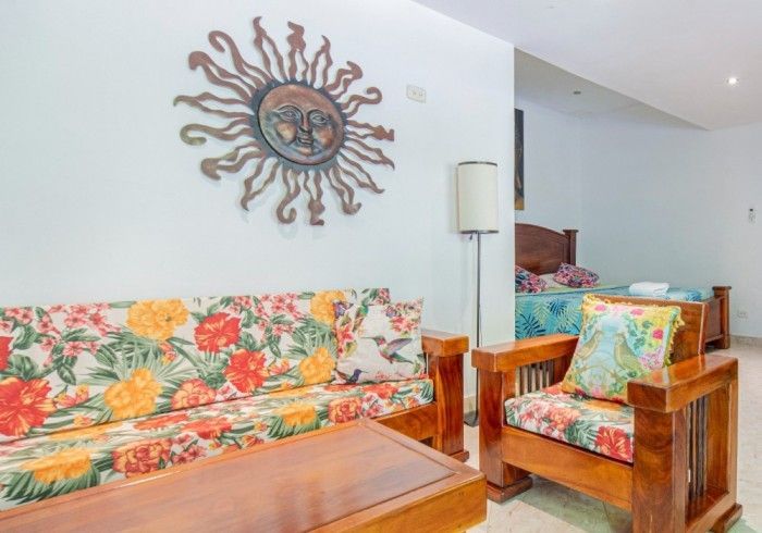 Una sala de estar con un sofá y sillas y un sol en la pared.