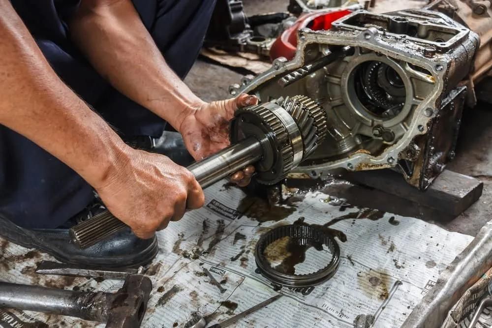 A Man is Working on a Gearbox in a Garage — C L Dickinson Auto Electrics In Narrabri, NSW