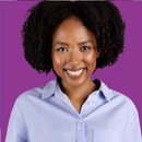 A woman with curly hair is smiling in front of a purple background