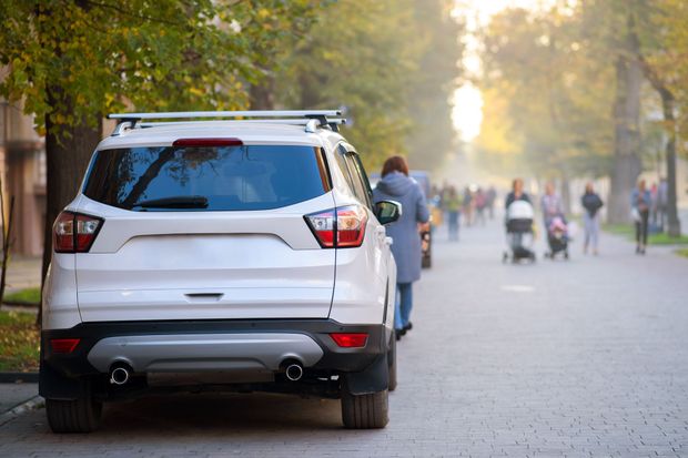 A white suv is parked on the side of the road in a park.