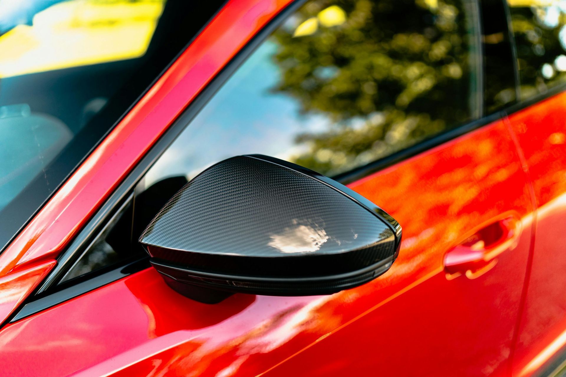 A close up of a red car 's side mirror.