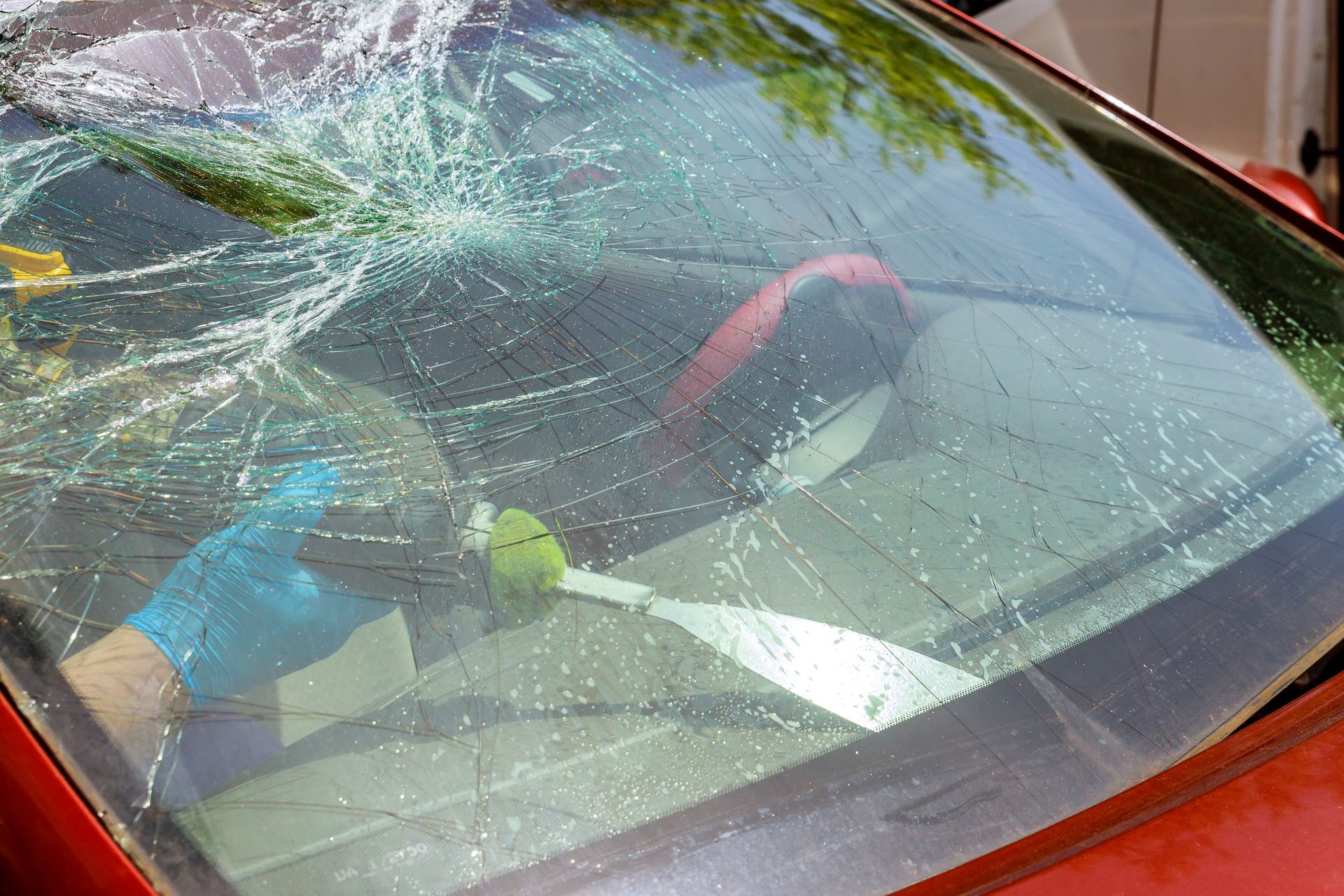 A close up of a broken windshield on a red car.