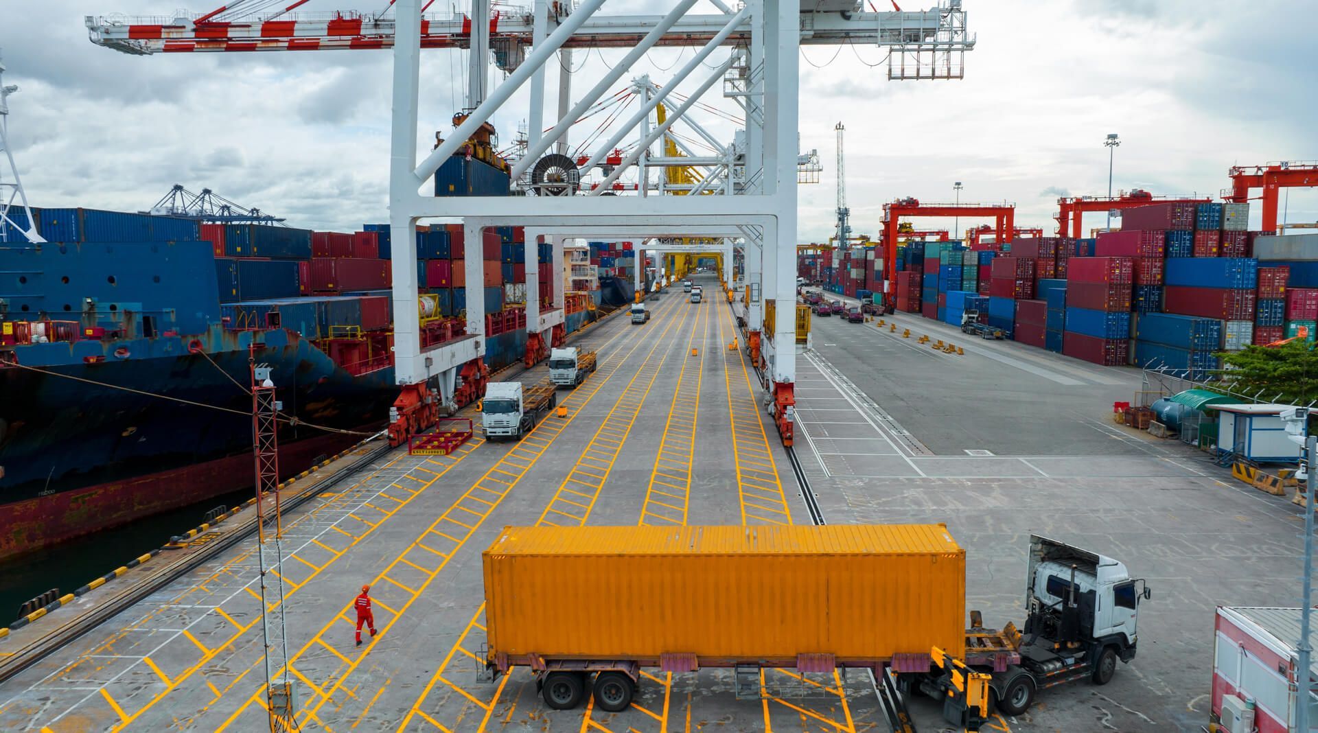 A truck is parked in front of a large ship in a harbor