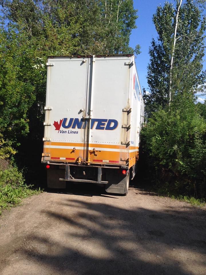 A truck is parked on the side of a dirt road