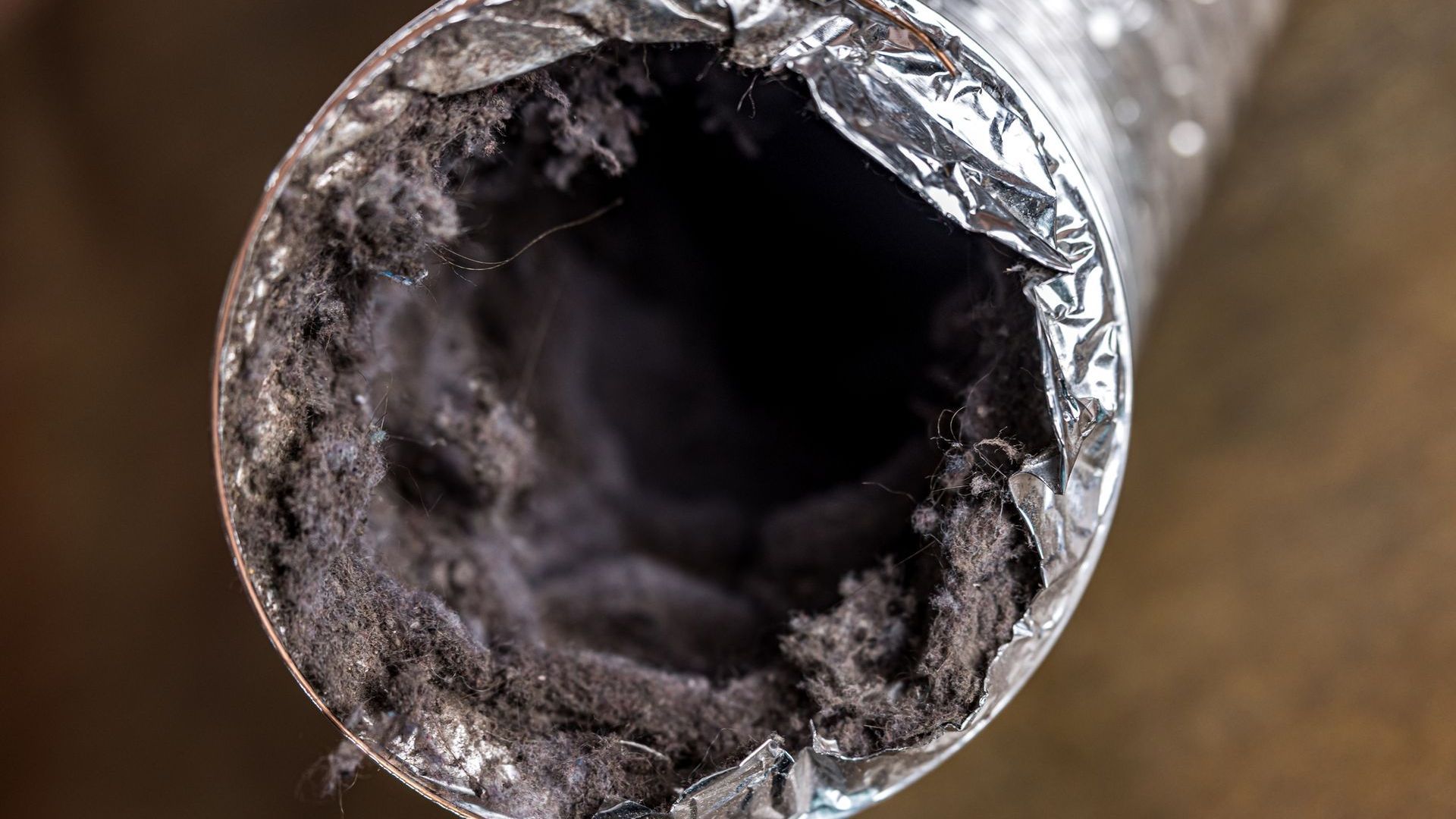 A close up of a dirty duct with dust coming out of it.