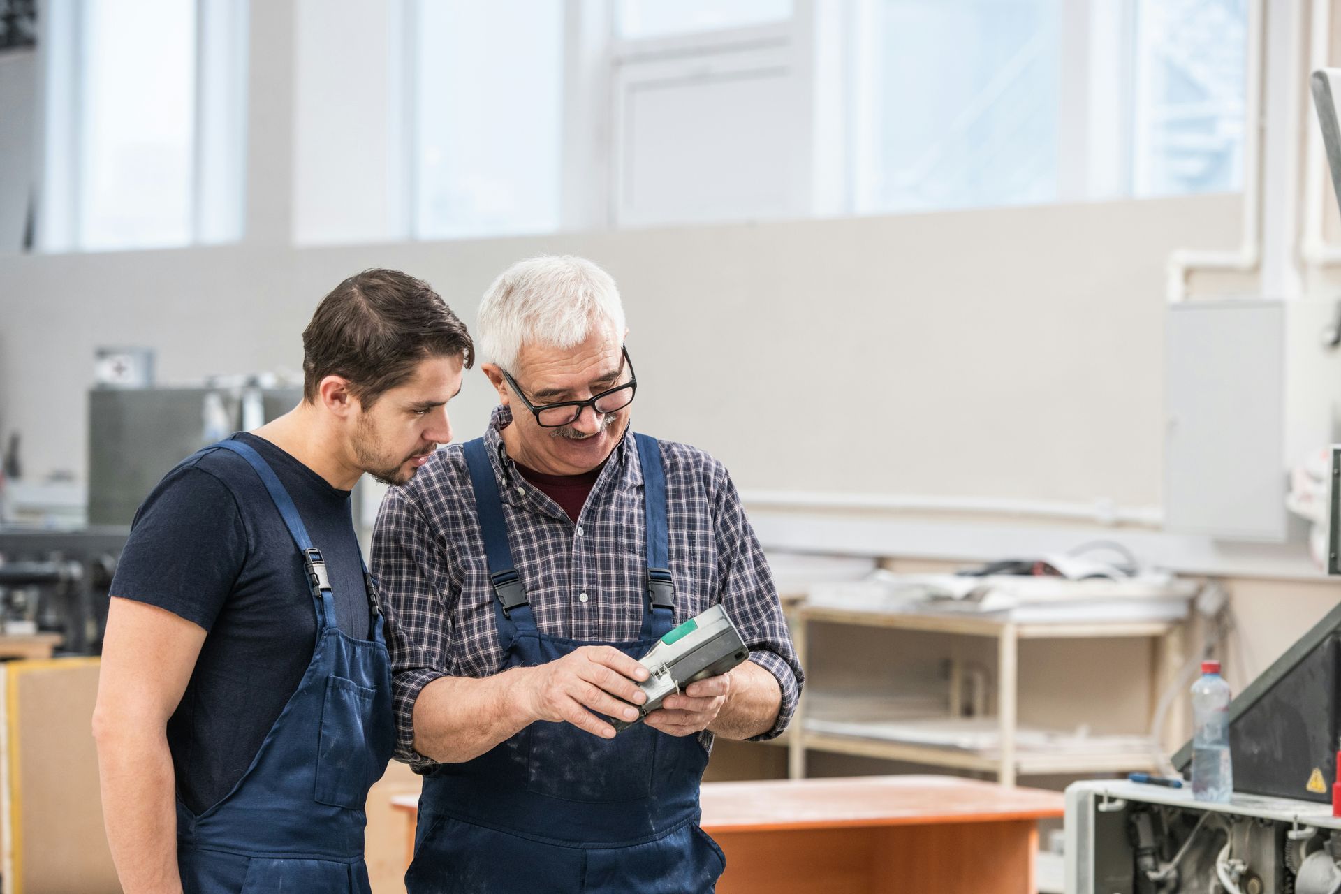 Two men are standing next to each other in a factory looking at a tablet.